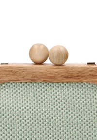Caja de madera con tapa de madera clara, textura tejida en verde pálido en el frente y dos acentos de madera redondeados en la parte superior. Diseño simple y geométrico.