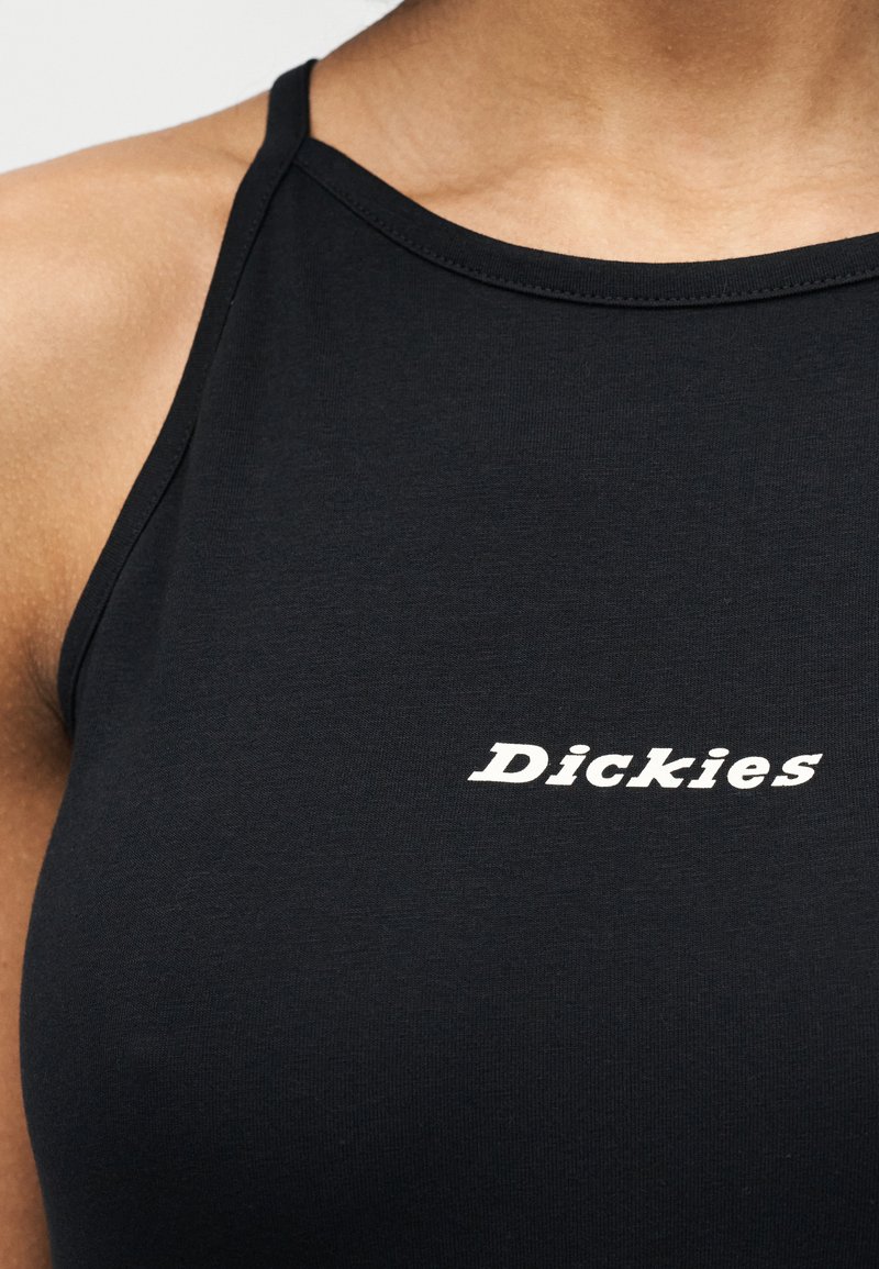 Close-up of a person wearing a black sleeveless top with white "Dickies" logo printed on the chest.