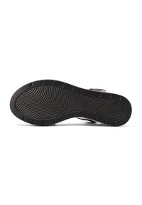Suola di scarpa in gomma nera con un motivo testurizzato, caratterizzata da scanalature per la presa e la stabilità. Il design è piatto con bordi arrotondati.