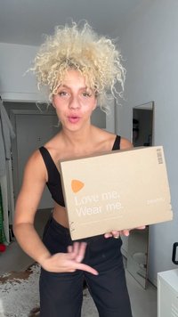 Caixa de cartão em castanho claro com o texto "Ame-me. Use-me." e o logótipo da Zalando. Apresenta um destaque triangular laranja, formato quadrado.