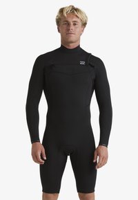 Traje de neopreno negro hecho de material elástico, con mangas largas, piernas cortas, cierre de cremallera y un logo minimalista en el pecho.