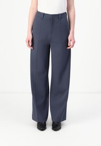 Wide-leg, navy trousers made from textured fabric. Features a flat front, belt loops, and crease detailing along the legs.