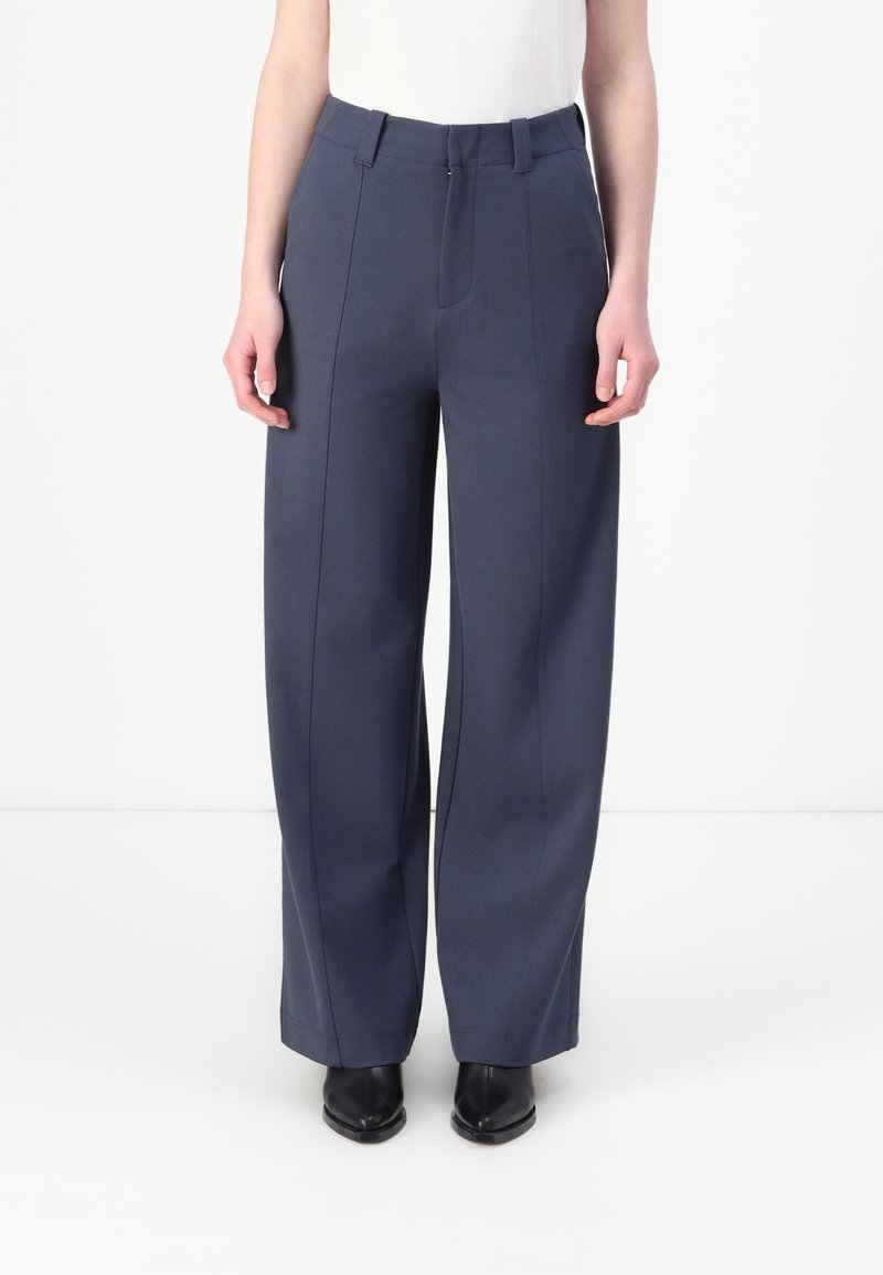Wide-leg, navy trousers made from textured fabric. Features a flat front, belt loops, and crease detailing along the legs.