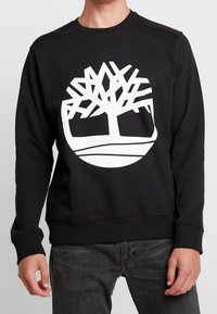 Felpa nera con grande logo a forma di albero bianco, collo rotondo, polsini e orlo a costine, realizzata in morbido tessuto testurizzato.