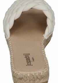 White braided sandal with a jute sole and a soft insole. Features stitching along the edges and a flat, open design for easy wear.