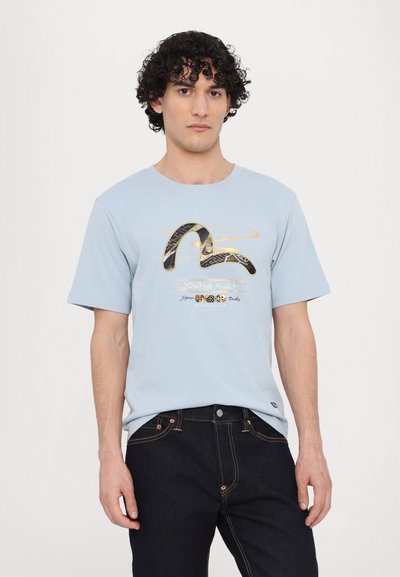 Tricou din bumbac de culoare albastru deschis, cu mâneci scurte, având un design abstract negru și auriu în partea din față și decolteu rotunjit.