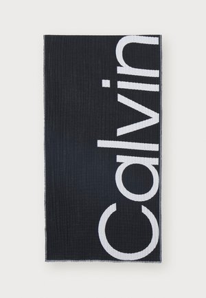 Black towel featuring large white text "Calvin" on one side. Textured surface with hemmed edges and a simple, modern design.