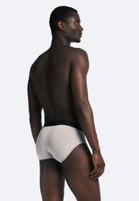Caleçons en coton gris avec une taille noire, affichant un design ajusté et une texture lisse, vus de l'arrière.