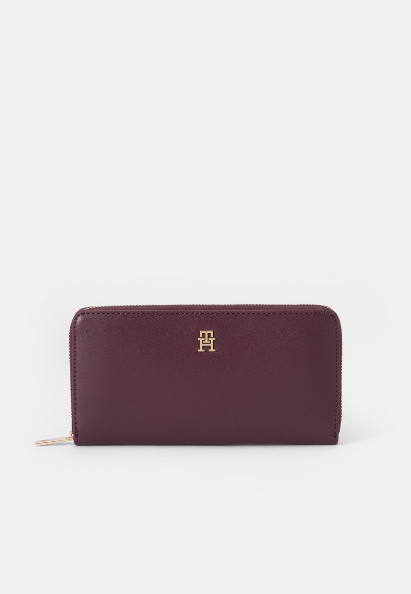 Portofel din piele burgund cu logo-uri din aur. Inchidere cu fermoar, textură netedă și formă rectangulară. Design plat pentru o stocare ușoară.