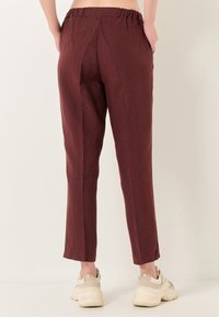 Pantaloni bordeaux con vestibilità rilassata, vita elastica, tasche laterali e design a gamba dritta, realizzati in tessuto testurizzato.