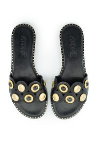 Schwarze Badeschuhe mit einer strukturierten Oberseite, die runde Akzente in Gold, Creme und Dunkelblau aufweist, sowie dekorative goldene Nieten entlang der Sohle.