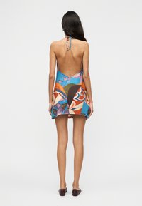 Χρωματιστό φόρεμα με λαιμόκοψη halter, με ανοιχτή πλάτη, λουλουδένια και αφηρημένα σχέδια σε μπλε, πορτοκαλί και πράσινο, κατασκευασμένο από ελαφρύ ύφασμα.