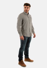 Zwart-wit geblokt overhemd met knopen, slim fit, van katoenen stof, lange mouwen, gecombineerd met donkerblauwe jeans en lichtbruine enkellaarsjes.