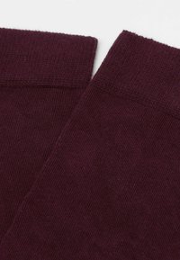 Burgundy bomullssockor med ribbad textur, med färdiga mudd och en slät yta. Inga synliga mönster eller metalliska detaljer.