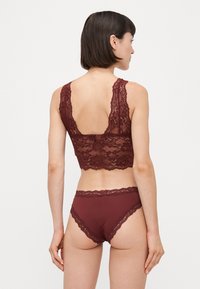 Burgundy lace bralette with wide straps and floral pattern, paired with matching high-waisted brief featuring scalloped lace edges.