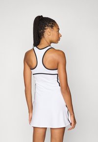 Λευκό αθλητικό φόρεμα με μαύρες λεπτομέρειες, εφαρμοστή γραμμή, στυλ racerback και φουσκωτή φούστα. Ομαλό ύφασμα με ελάχιστες ραφές.