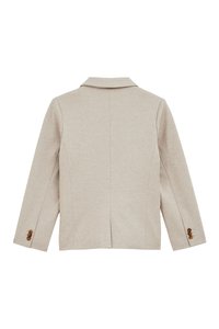 Šviesiai smėlio spalvos bleizeris su įpjovimu, struktūruotais petukais ir dviem sagomis ant rankovių. Lygus audinys su raukšlėmis ant nugaros.