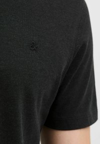 Zwart T-shirt met korte mouwen, gemaakt van een textuurstof en met een subtiele logo-details. Het shirt heeft een ronde halslijn en een aansluitende pasvorm.