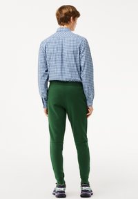 Blå och vit rutig skjorta, åtsittande med krage, matchad med gröna tapered sweatpants. Sneakers med lila och gröna accenter.