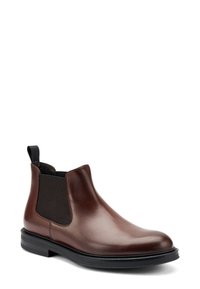 Stivale Chelsea in pelle marrone con pannelli laterali elasticizzati e un tab per l'estrazione. Texture liscia con punta arrotondata e suola in gomma nera.