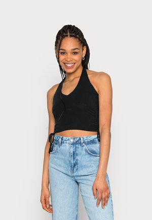 Top cropped preto de halter com um design em v e laços laterais, combinado com jeans de ganga azul claro de cintura alta, apresentando bolsos clássicos.