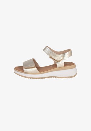 Sandalia femenina metálica dorada con punta abierta, correas ajustables en el tobillo y en el empeine, plantilla acolchada y suela plataforma blanca con dibujo beige.