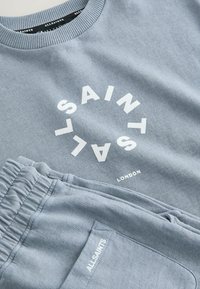 Sweat-shirt en coton bleu clair et pantalon de survêtement assorti avec logo AllSaints blanc et texte "London" sur le sweat-shirt.