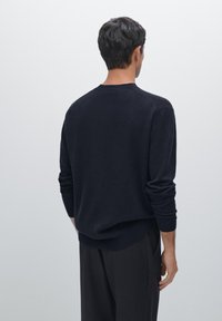 Marineblauer Pullover mit lockerer Passform, Rundhalsausschnitt und langen Ärmeln, von hinten gezeigt. Das Material scheint weich mit einer glatten Textur zu sein.