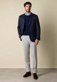 Námořnický jednobarevný blejzr, námořnický svetr, světle modrá košile s límečkem, světle šedé kalhoty, hnědé mokasíny. Hladká tkanina, přiléhavý střih.