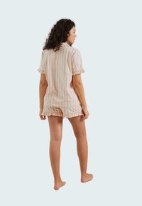 Ensemble de pyjama à manches courtes, rayé, en tissu doux. Comprend des manches à volants et un ourlet de short, avec des rayures alternées rose et blanc.
