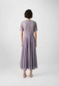 Lilla kleit, millel on pitsist bodice ja voolav šifoonseelik. Lühikesed varrukad, kehakujuline talje ja täispikk siluett. Klassikaline disain.