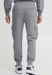 Gray joggers made of soft fabric, featuring side cargo pockets, elastic cuffs, and a relaxed fit design for comfort.