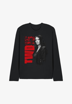 Schwarzes Langarmshirt mit einer grau gestalteten Frau mit dunklen Haaren und Jacke, hinter der teilweise in fetten roten vertikalen Buchstaben "TWD" zu sehen ist.