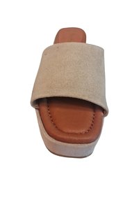 Sandalia deslizante de ante beige con una amplia correa cruzada, una plantilla acolchada marrón y una gruesa suela de plataforma blanca. Diseño minimalista sin adornos.