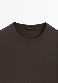 Donkerbruin T-shirt met ronde hals, dubbele stiksels aan de kraag en een ingenaaid label met de tekst "Massimo Dutti Made in Portugal."