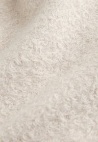 Tissu doux de couleur crème avec une surface bouclée et texturée ressemblant à de la laine polaire ou du bouclé.