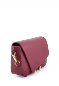 Maroon leren handtas met een klep sluiting, gouden hardware en een afneembare strap. Geproduceerd met een gestructureerd oppervlak en een minimalistisch ontwerp.