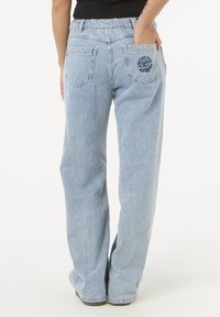 Lyseblå denimjeans med avslappet passform, med elastisk midje og to baklommer, hvorav den ene er prydet med blomsterbroderi.