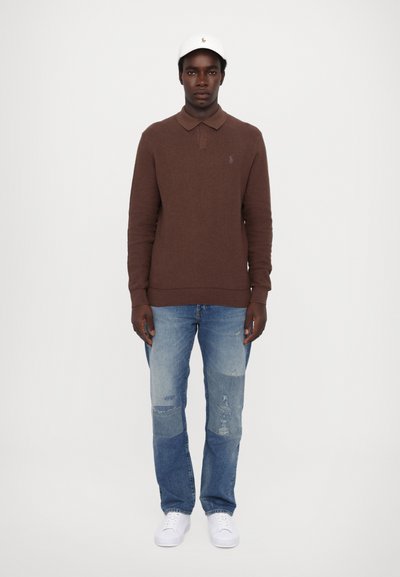 Brun langærmet polo skjorte med krave, parret med lyseblå slidte jeans og hvide sneakers, suppleret med en hvid kasket.