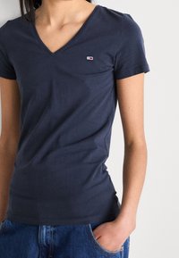 Námořnické modré tričko s krátkým rukávem a výstřihem do V vyrobené z bavlněné směsi, s malým logem na hrudi a přiléhavým střihem.