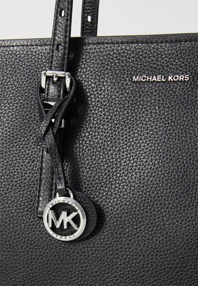 Sac fourre-tout en cuir noir avec une finition texturée, quincaillerie en argent et un charme logo MK attaché à une sangle. Dispose de bretelles robustes.