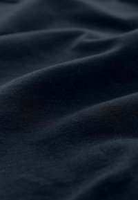 Mörk marinblått tyg med en jämn textur och subtila vågor, som visar fina trådar och en något reflekterande yta.
