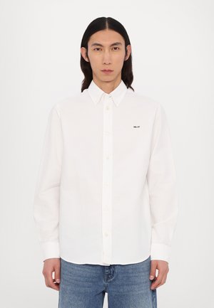 White button-up shirt made of cotton with a pointed collar, featuring a small black logo "NH. 07" on the left chest area.