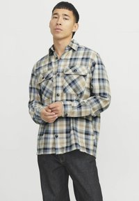 Leichtes Flanellshirt in blau, beige und schwarz kariert. Mit zwei Brusttaschen und Knopfschluss. Lange Ärmel mit knöpfbaren Manschetten.