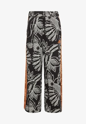 Pantalones negros de pierna ancha con patrón floral blanco y franjas laterales naranjas, con un pequeño logo naranja de Adidas en el muslo derecho.
