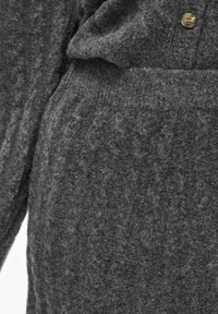 Grijze gebreide trui met een gestructureerd patroon, knoopsluiting en zacht, fluffy materiaal. Close-up van de details van de stof.