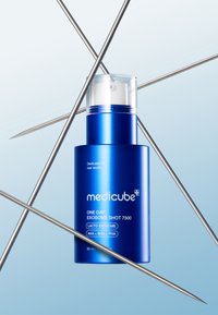 Bottiglia cilindrica blu con tappo a pompa trasparente, etichettata "One Day Exosome Shot 7500", circondata da sottili aghi argentati su uno sfondo sfumato.