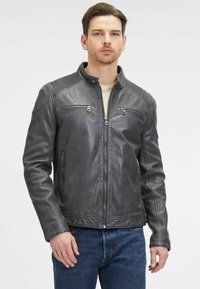 Giacca in pelle grigia con zip frontale, dettagli sulle spalle e due tasche sul petto. Texture liscia con dettagli a costine sulle spalle.
