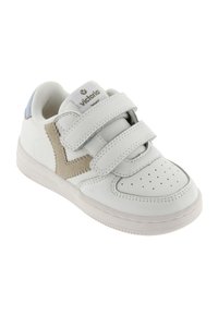 Witte sneaker met twee klittenbandsluitingen, geperforeerde neus en beige suède accent. Heeft een lichtblauwe hiel en een gestructureerde rubberen zool.