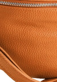 Oranje leren tas met een getextureerd oppervlak. Heeft een zilverkleurige rits en een eenvoudige, platte riem. Compact en afgerond van vorm.